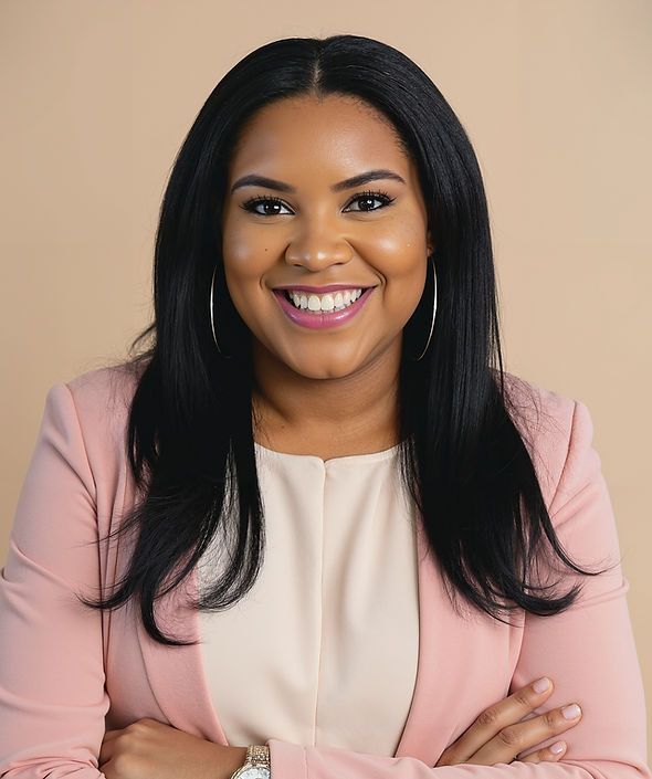 real estate agent sarita foxworth smiles, wearing a pink blazer, standing with arms crossed, against a neutral background.