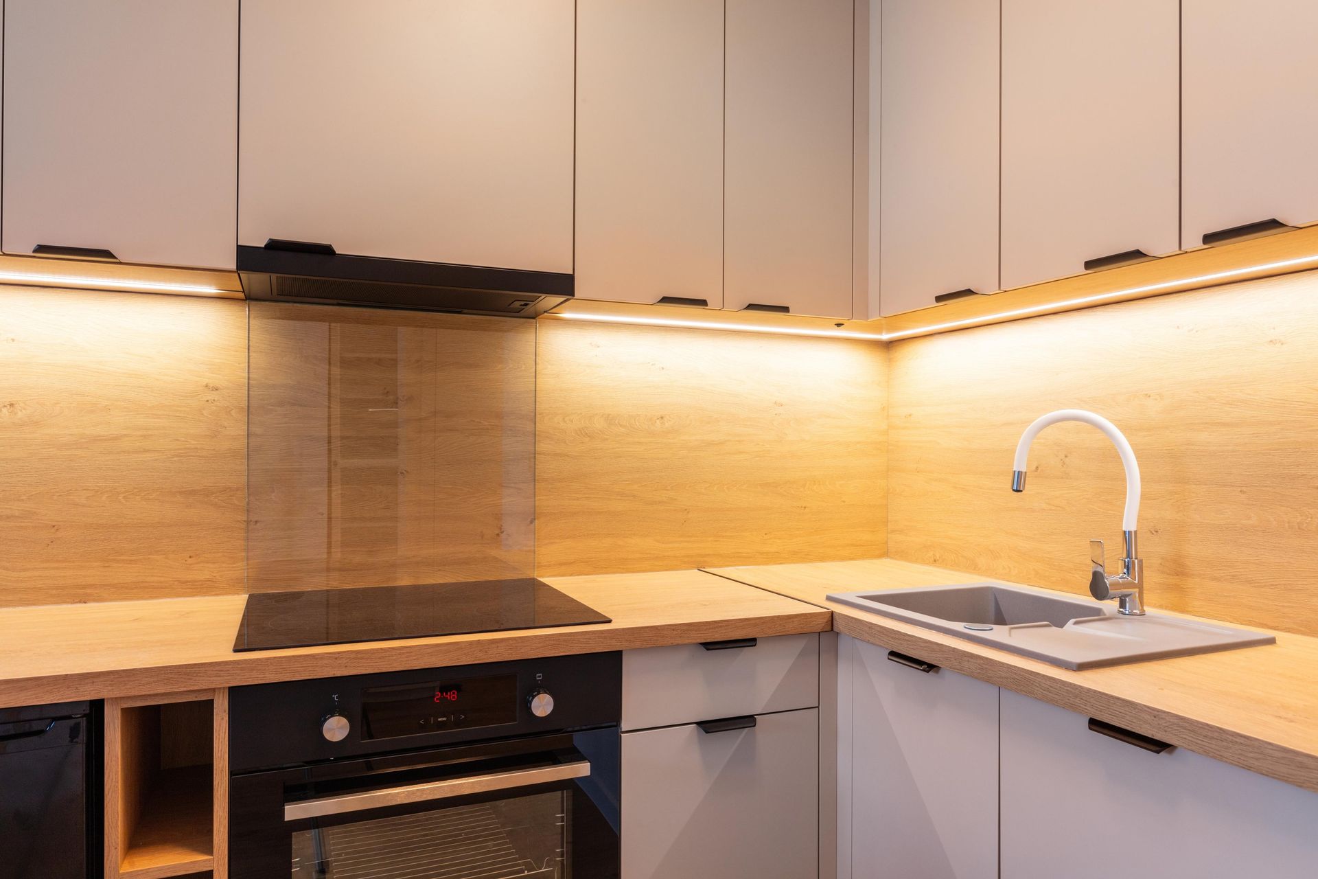 Modern kitchen corner with light wood countertops, grey cabinets, and a white sink.