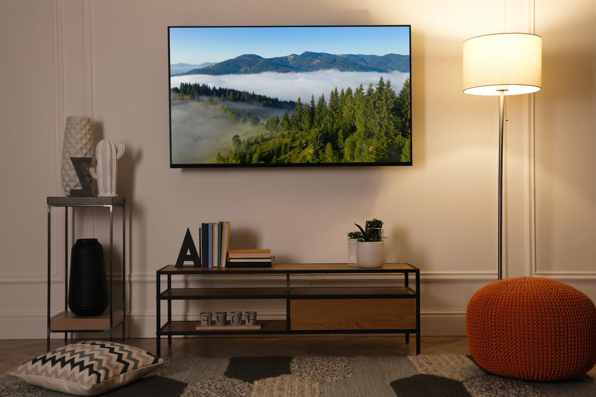TV displaying mountain scene above a console table with decor.