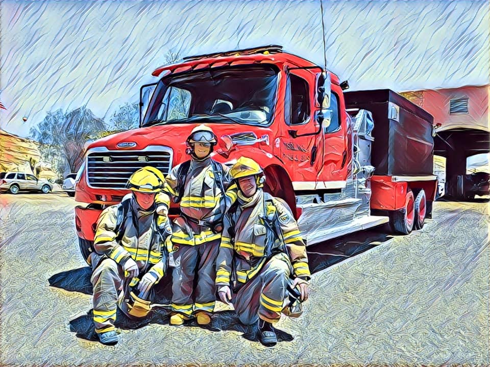 Three firefighters are posing for a picture in front of a fire truck.
