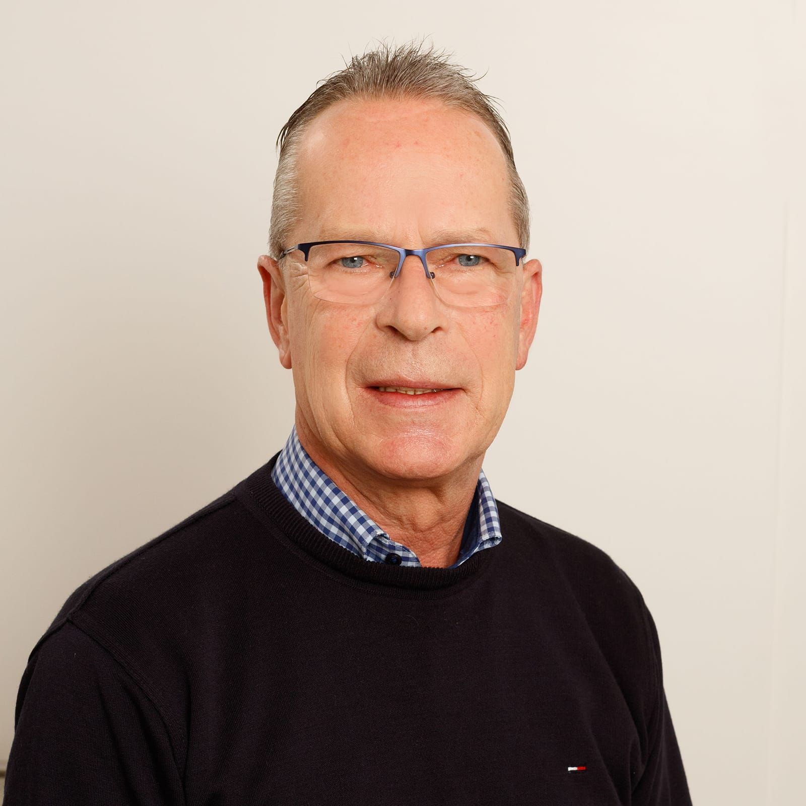 Ein Mann mit Brille und schwarzem Pullover lächelt in die Kamera.