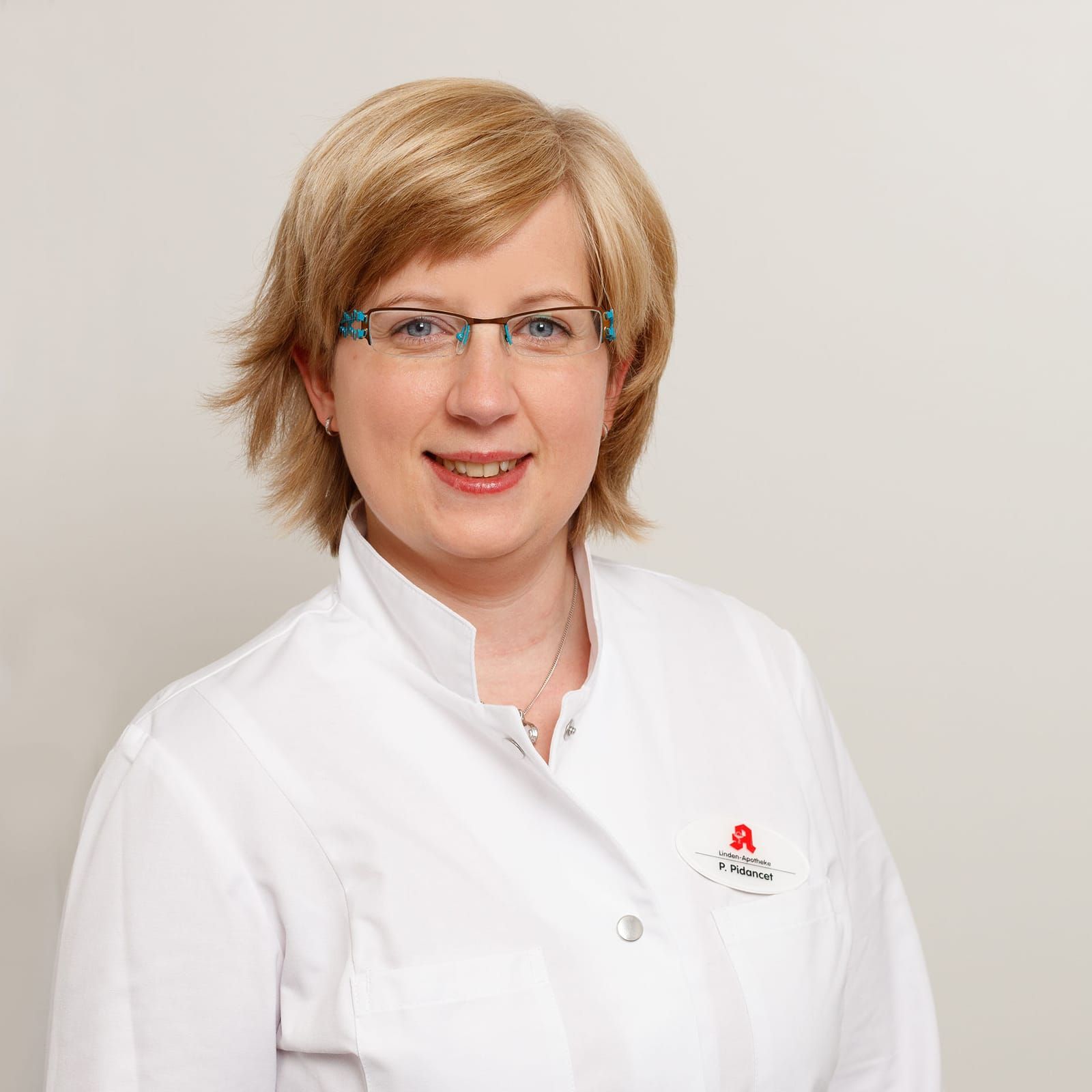 Eine Frau mit Brille und weißem Kittel lächelt in die Kamera