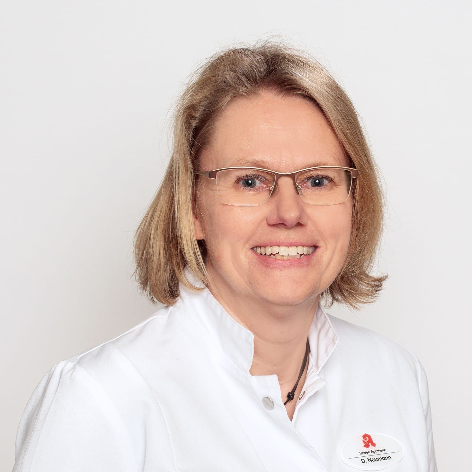 Eine Frau mit Brille und weißem Kittel lächelt in die Kamera.