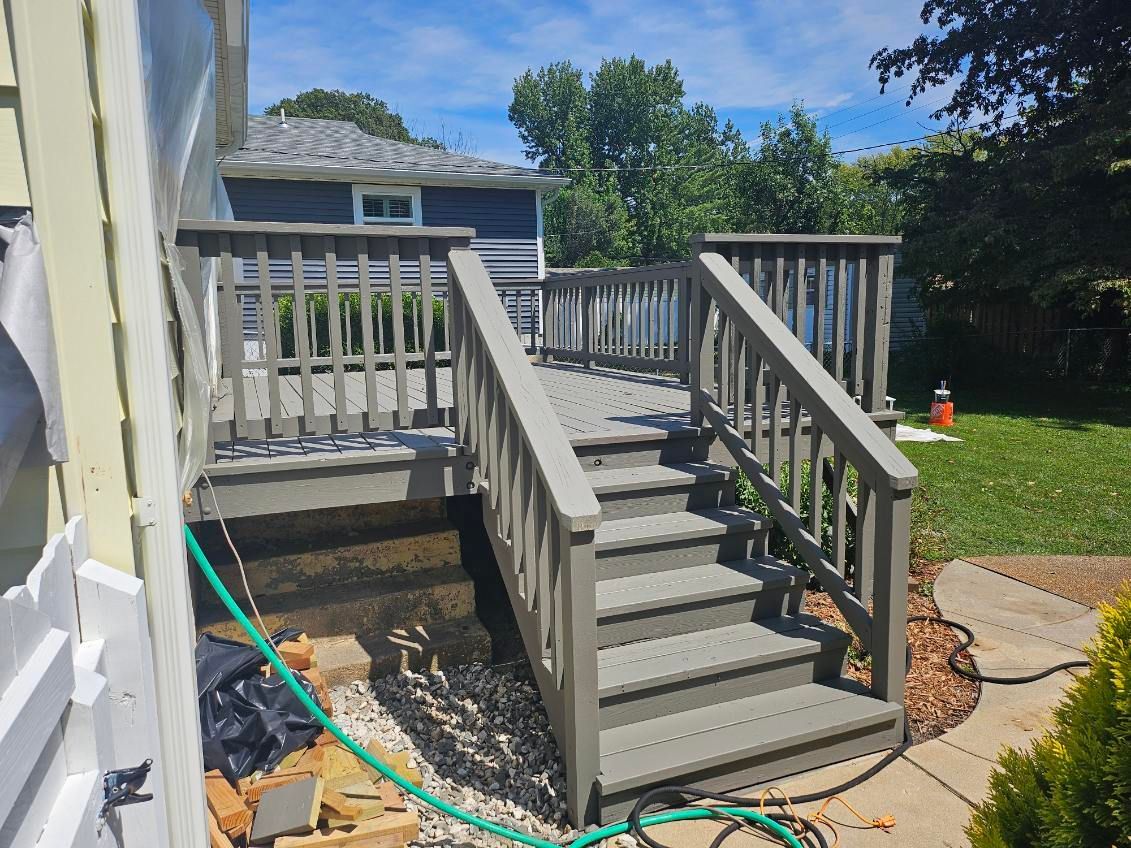 Grey wooden deck with steps leading down to a grassy yard. A house is visible in the background.