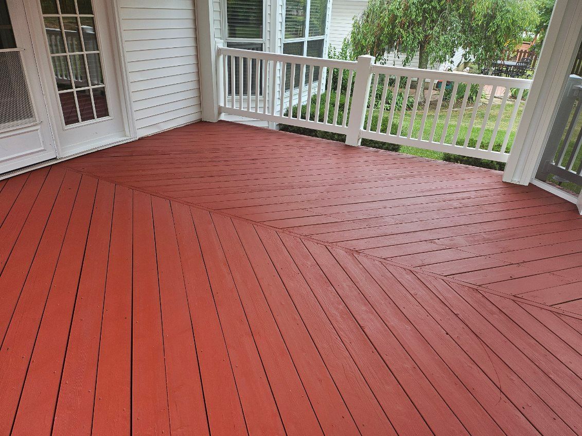 Red wooden deck with white railing and doors.