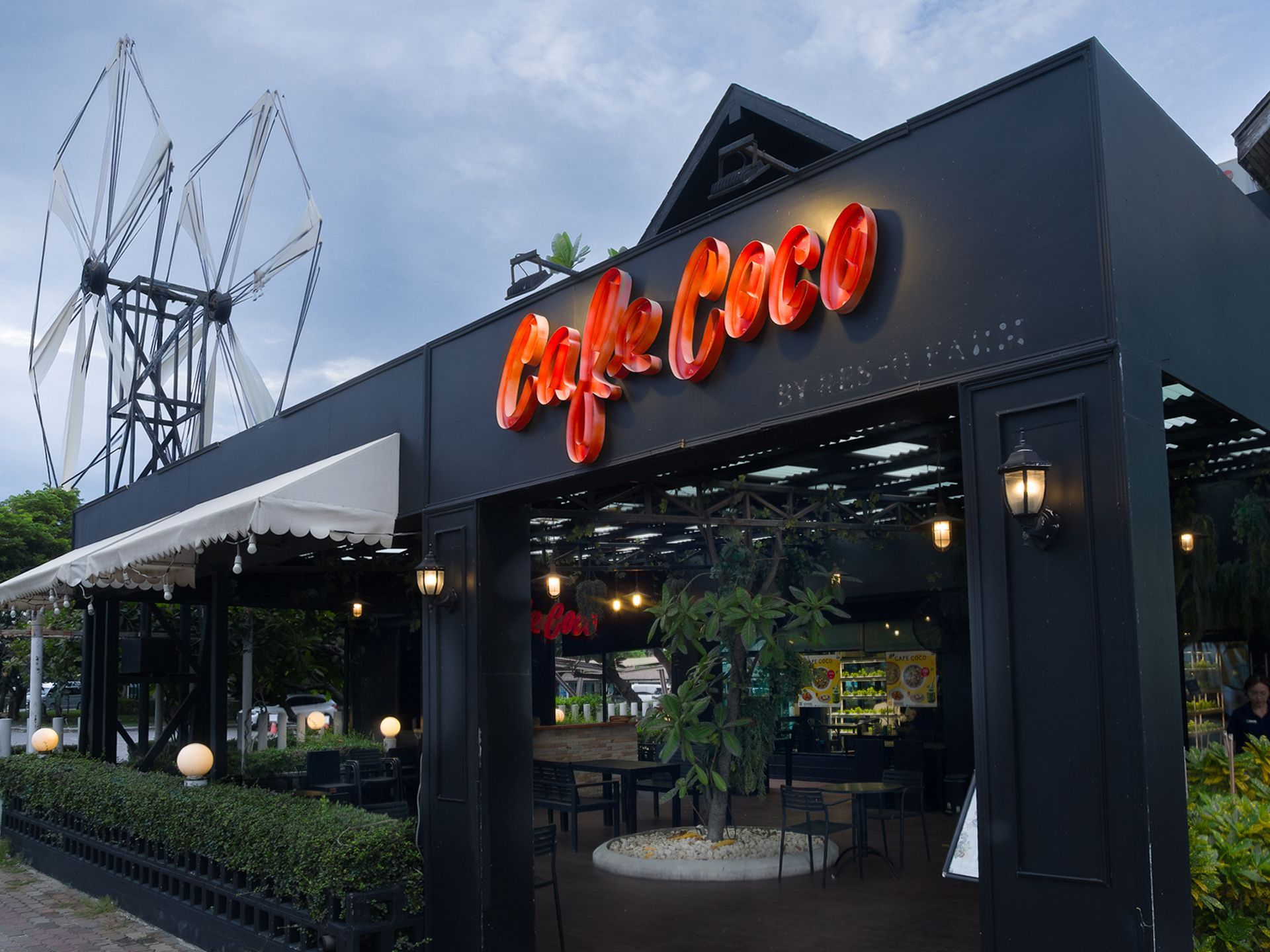 Cafe Coco 的外观，红色招牌，黑色建筑，遮阳篷，风车背景。