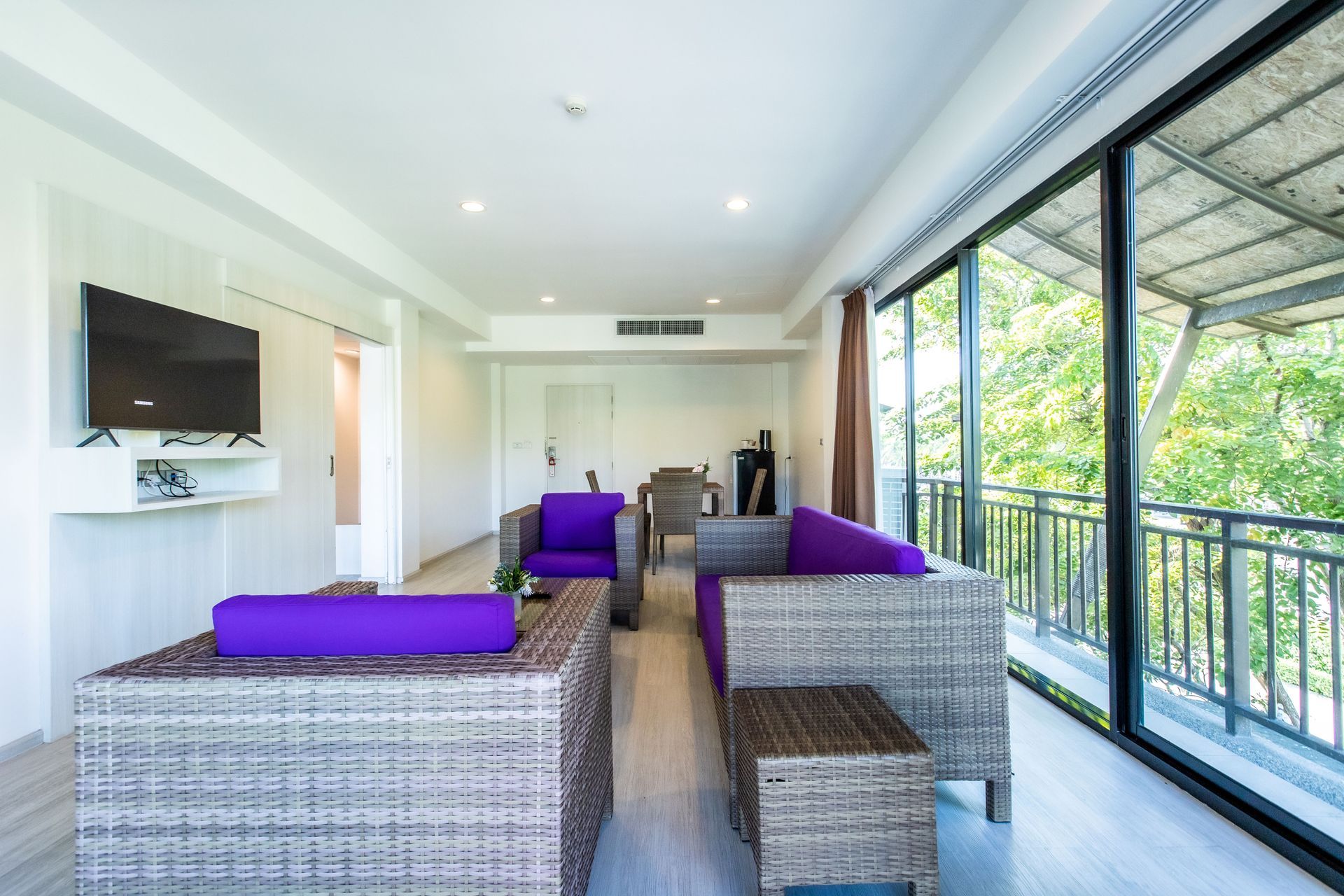 现代客厅，配有紫色藤制家具、大窗户和阳台。