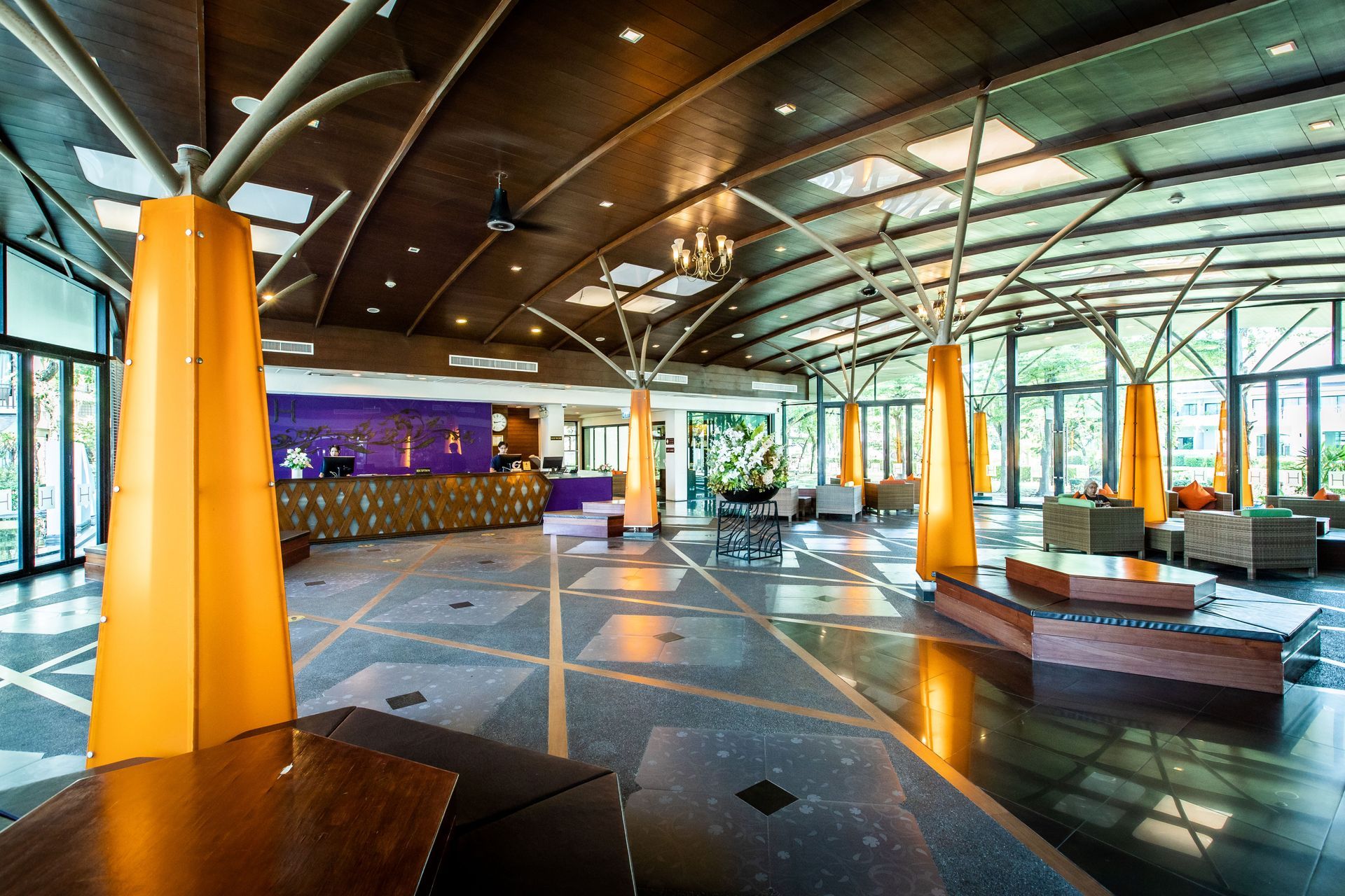 大厅设有橙色支撑柱、瓷砖地板、木质天花板和接待台。宽大的窗户让阳光洒满室内。