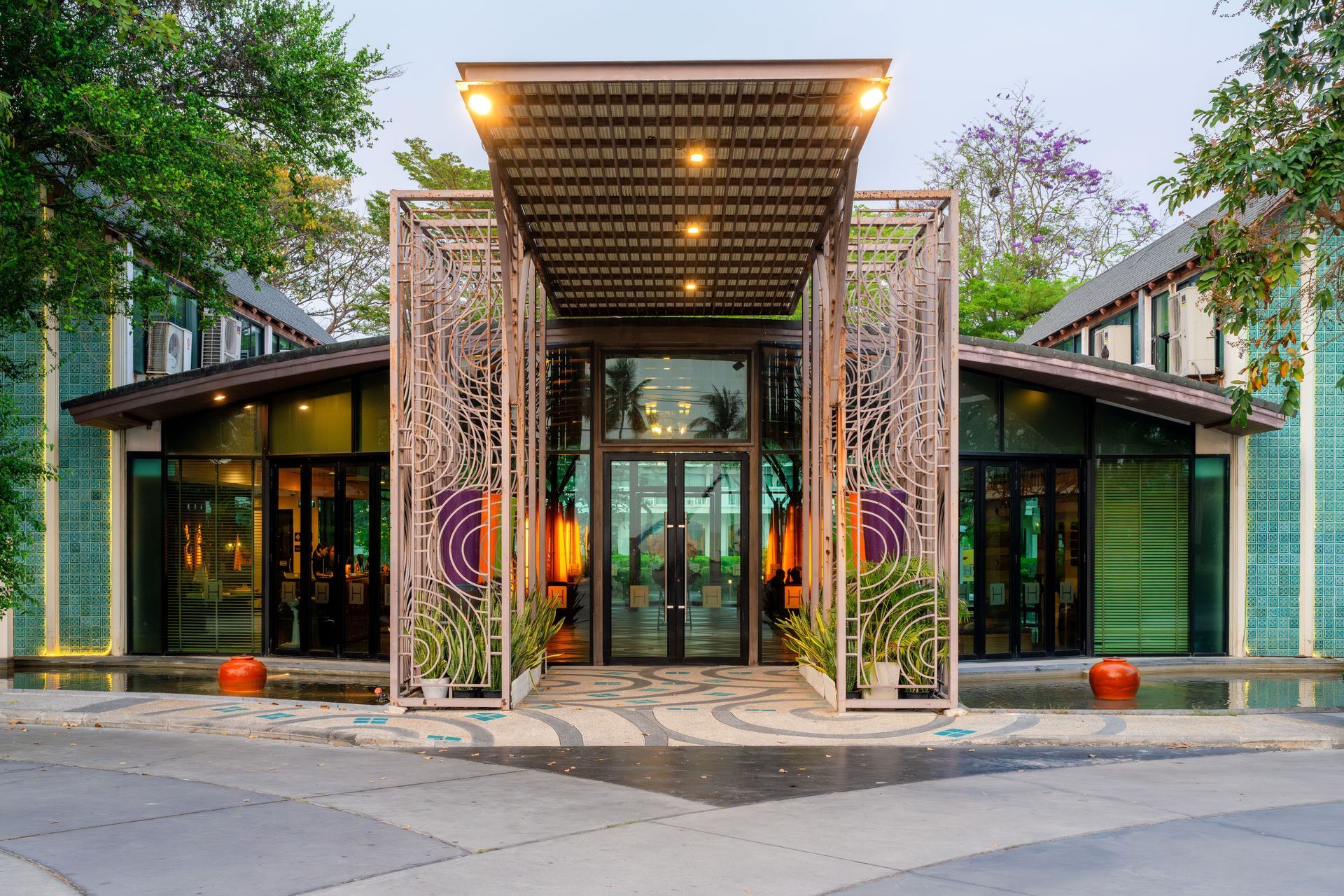 现代建筑入口，配有玻璃门、装饰性金属制品和周围绿植。