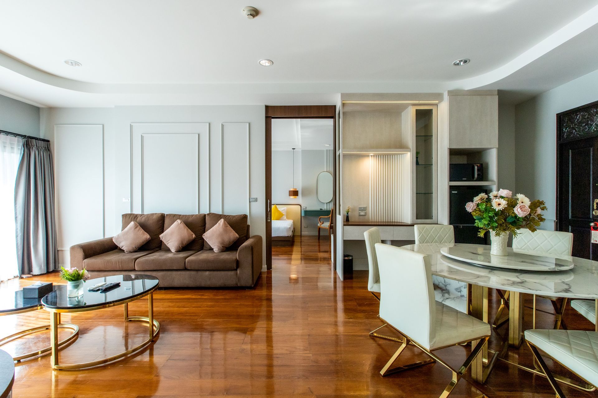 客厅里有一张棕色沙发、一张圆形餐桌，以及通往卧室的敞开式房门。