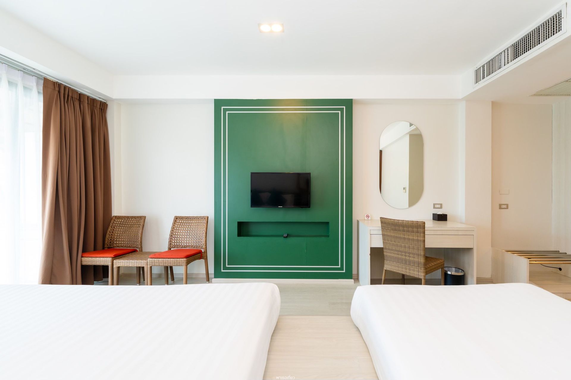 酒店房间内有两张床、一面绿色装饰墙和木制家具。