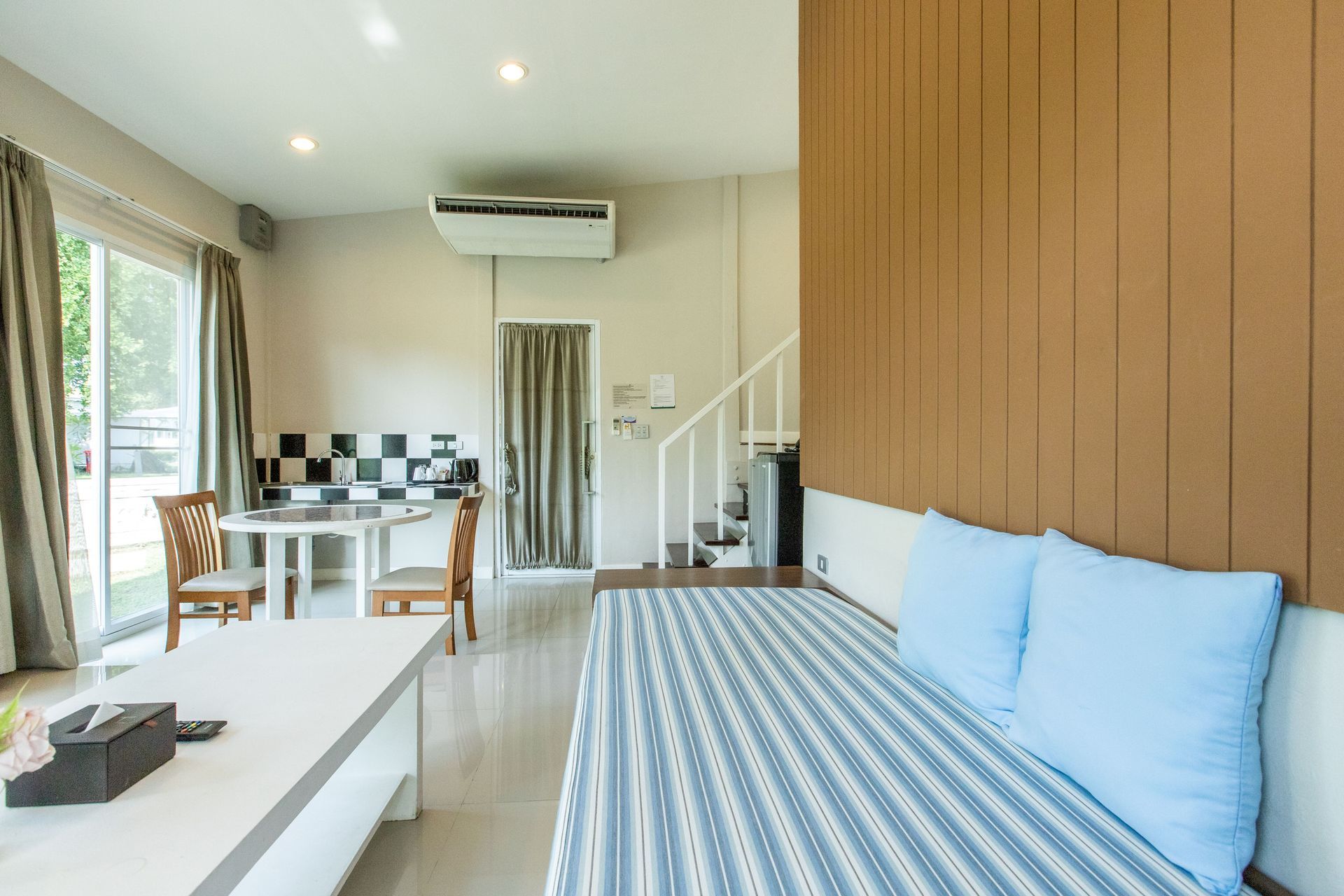 现代起居空间内部，设有厨房、沙发、餐桌和楼梯。