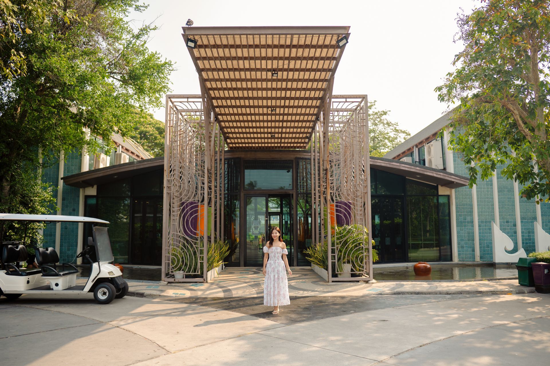 一名女子走向一栋带有装饰性花架的建筑入口。左侧停着一辆高尔夫球车。