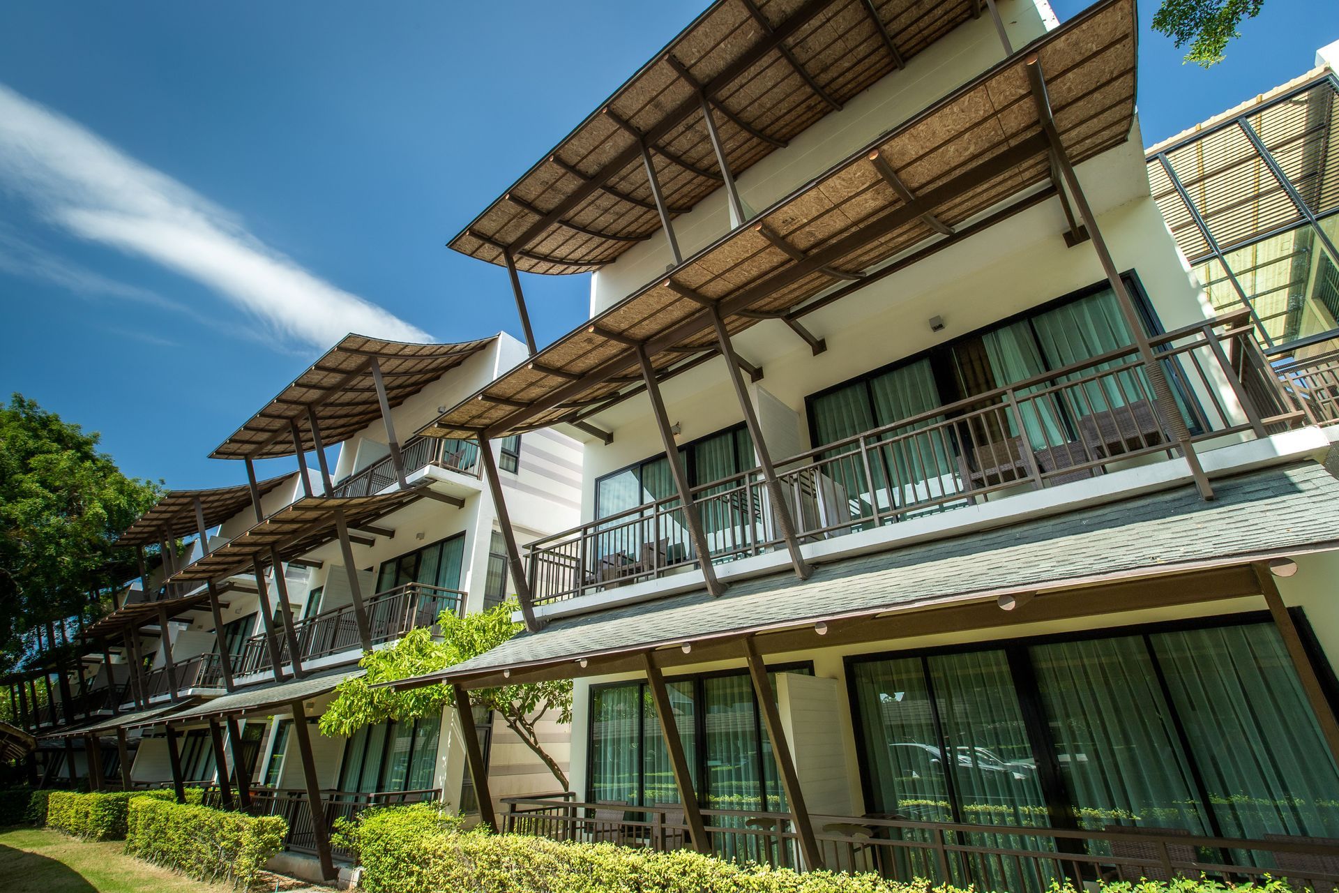 湛蓝的天空下，一座白色的酒店建筑，带有阳台和棕色的遮阳篷。