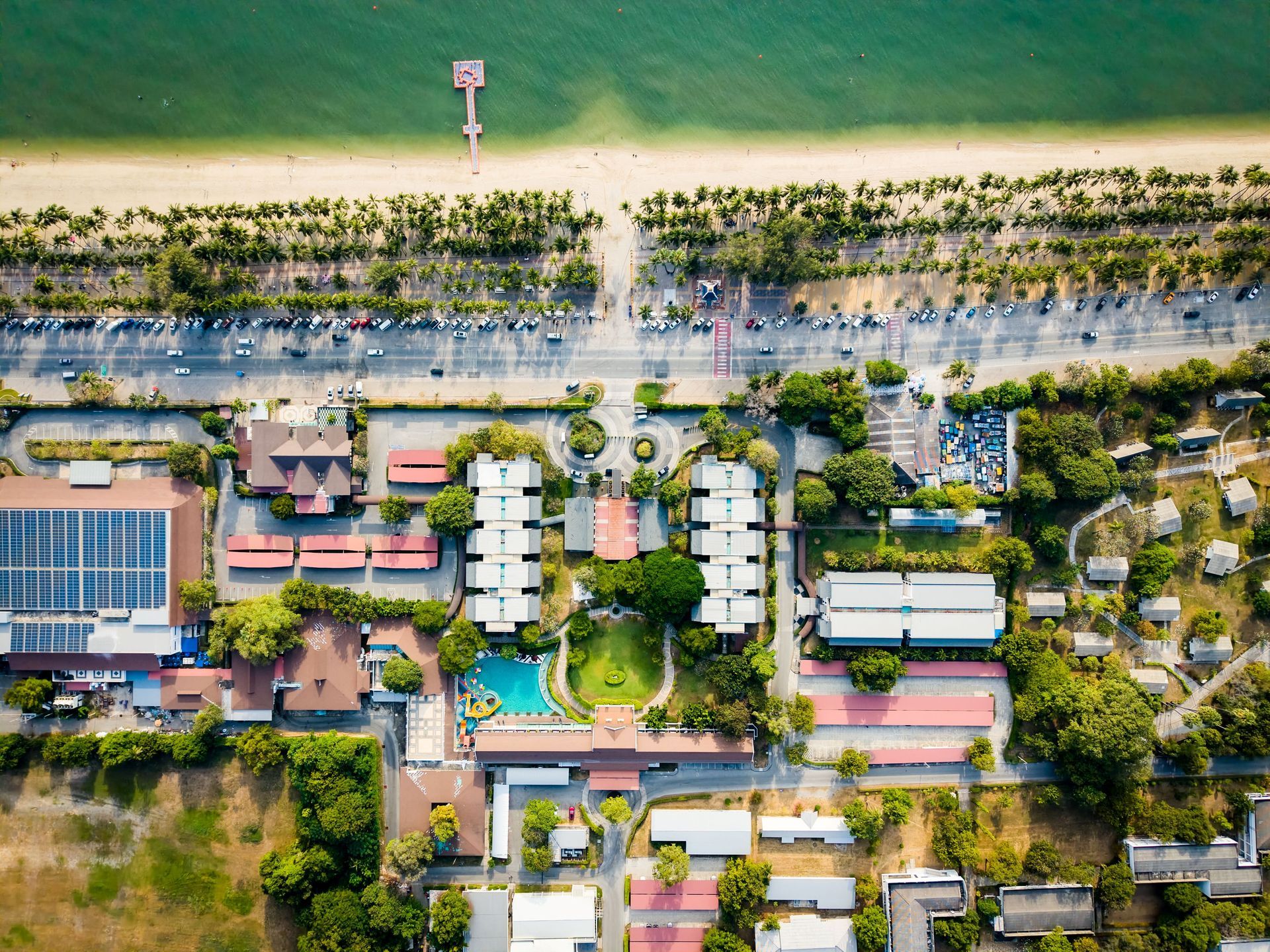 从空中俯瞰海滩，可以看到道路、建筑物和延伸到海中的码头。