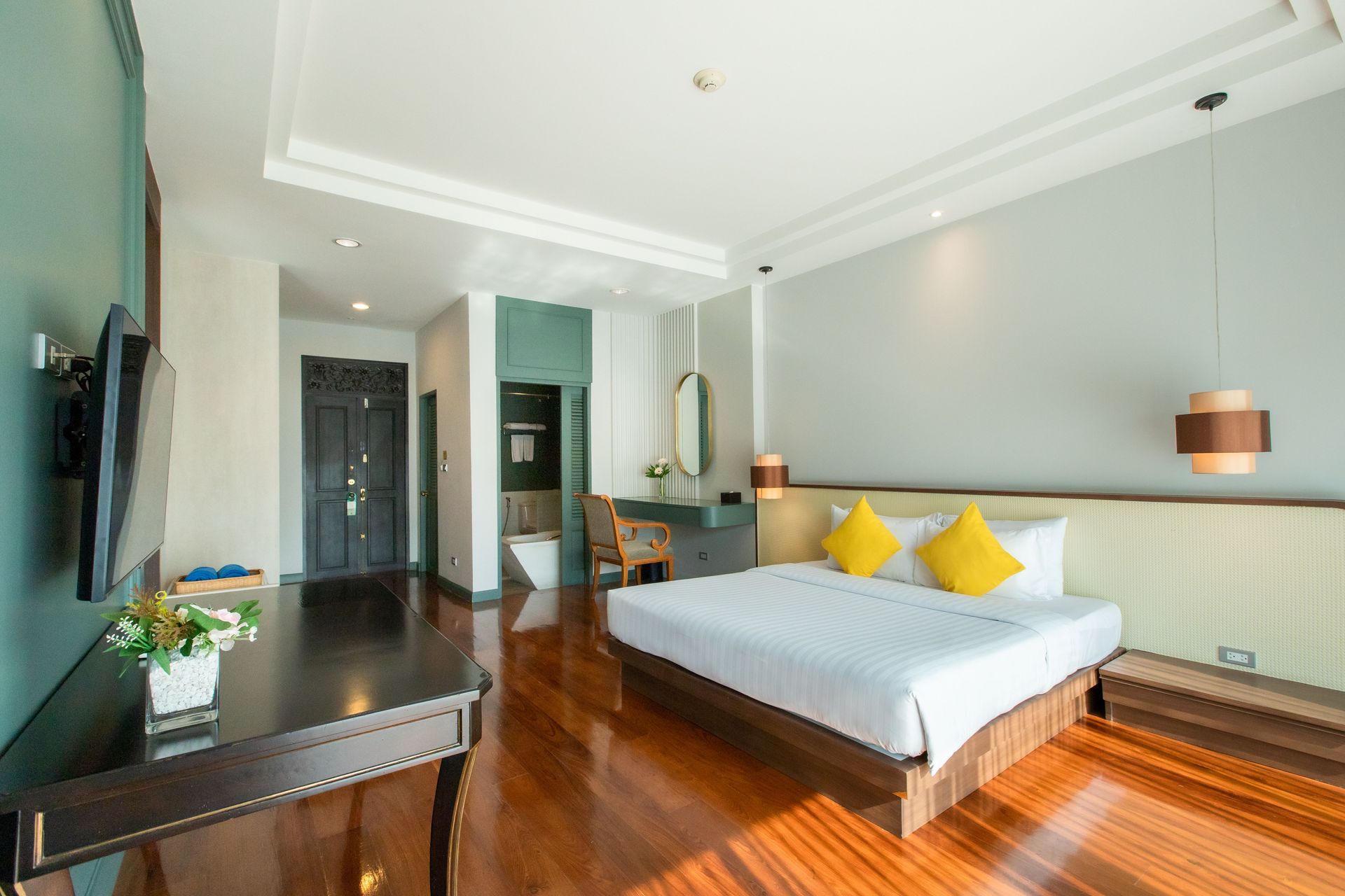 Hotel bedroom with hardwood floors, king bed, desk, and bathroom visible.