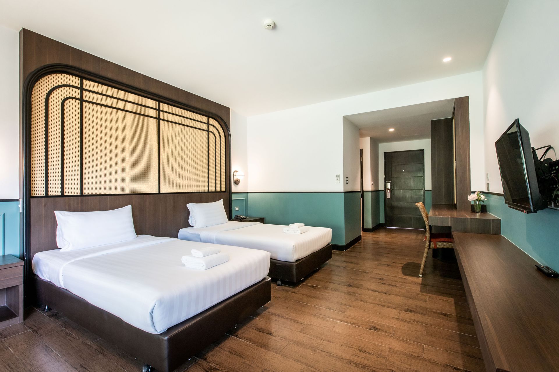 酒店房间配有两张单人床、深色木质装饰、蓝绿色装饰墙和一台电视。