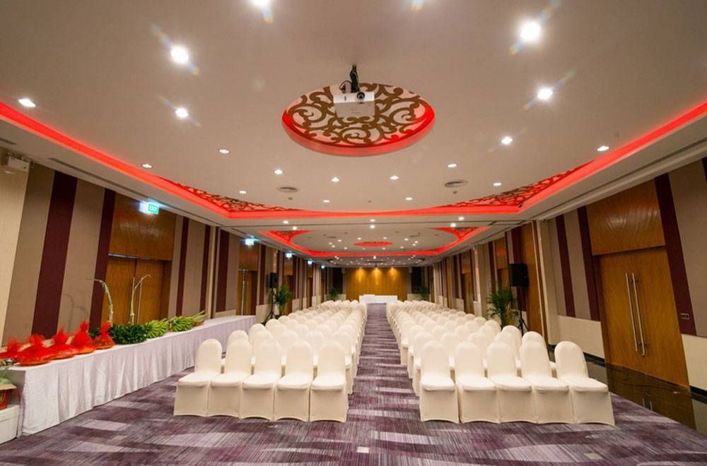 Conference room with rows of white chairs, red trim, and a projector.