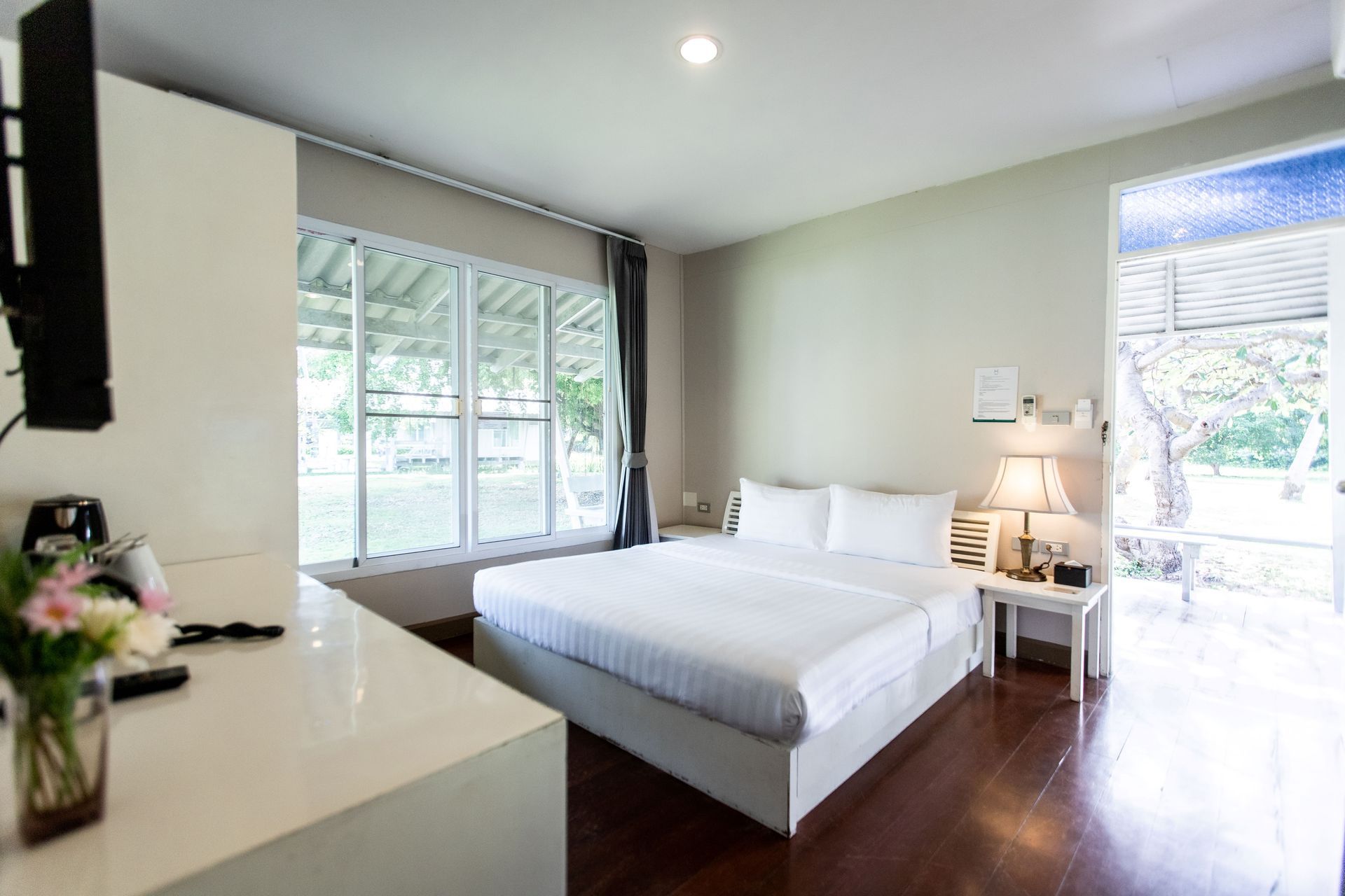 Bedroom with a bed, nightstand, large window, and open doorway to an outside patio.