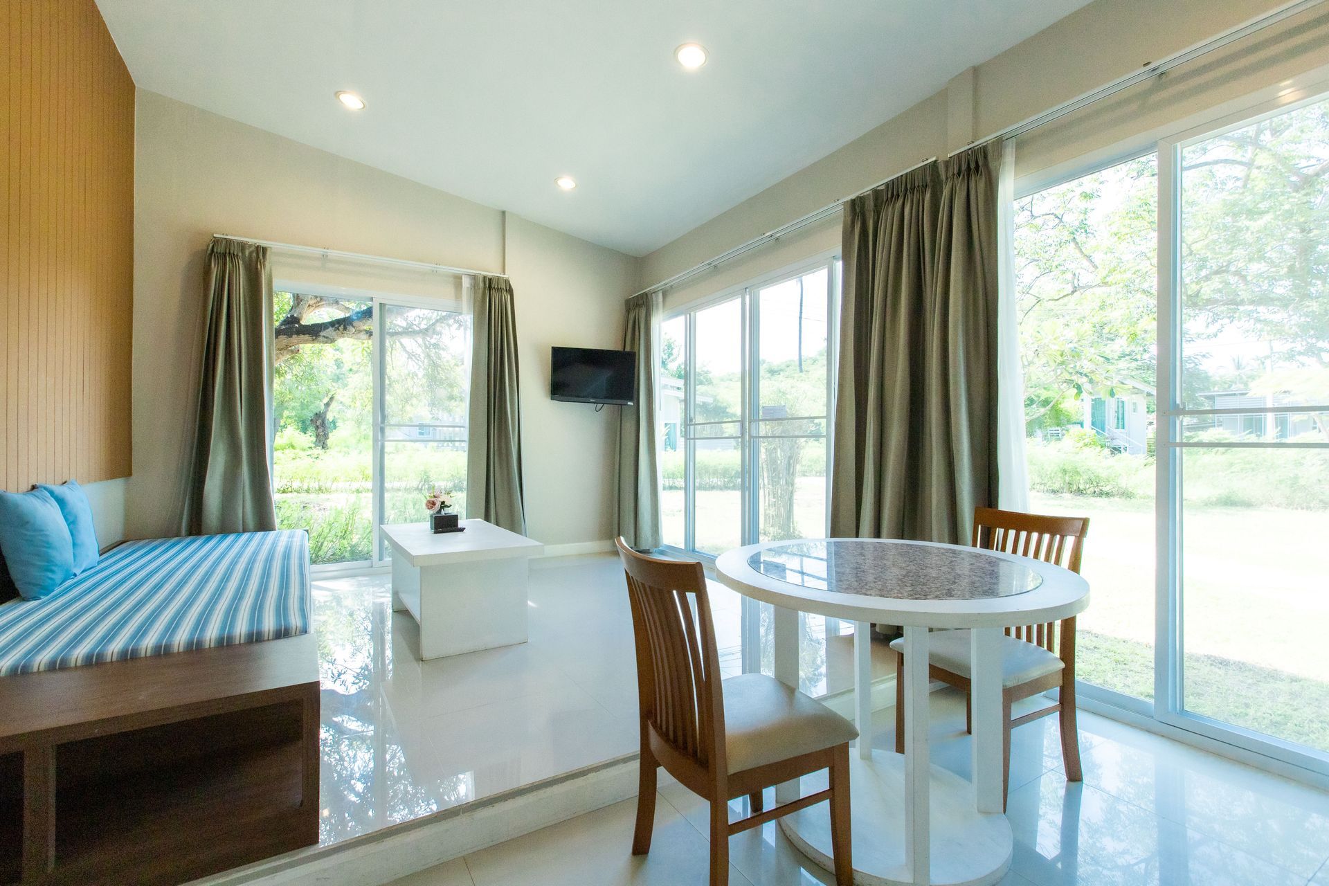 明亮现代的客厅，配有沙发、桌子、椅子和带窗帘的大窗户，可俯瞰花园。