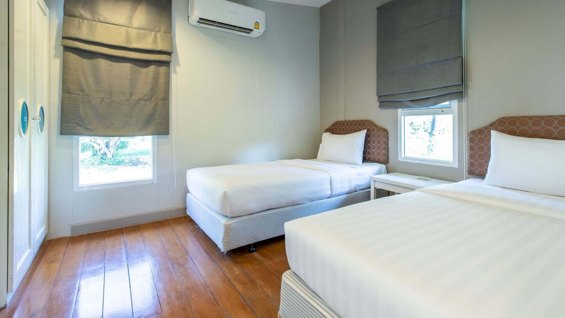 卧室配有两张单人床、硬木地板、带灰色百叶窗的窗户和白色内置衣柜。