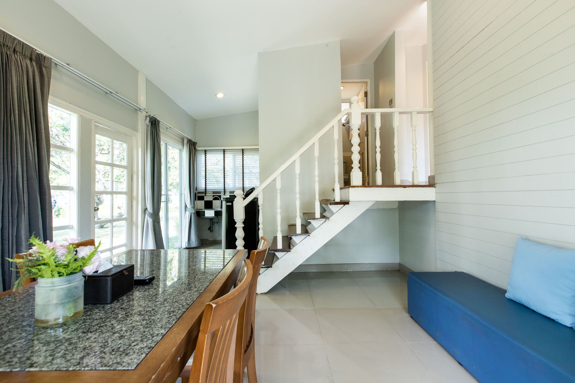 房屋内部景象，可见楼梯、餐桌和座椅。窗户和厨房也清晰可见。