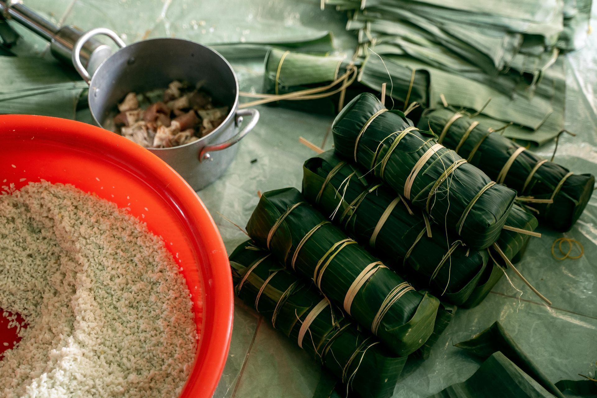 Preparing Vietnamese cylindrical banh tet cakes with wrapped ingredients, rice, and cooking pots.