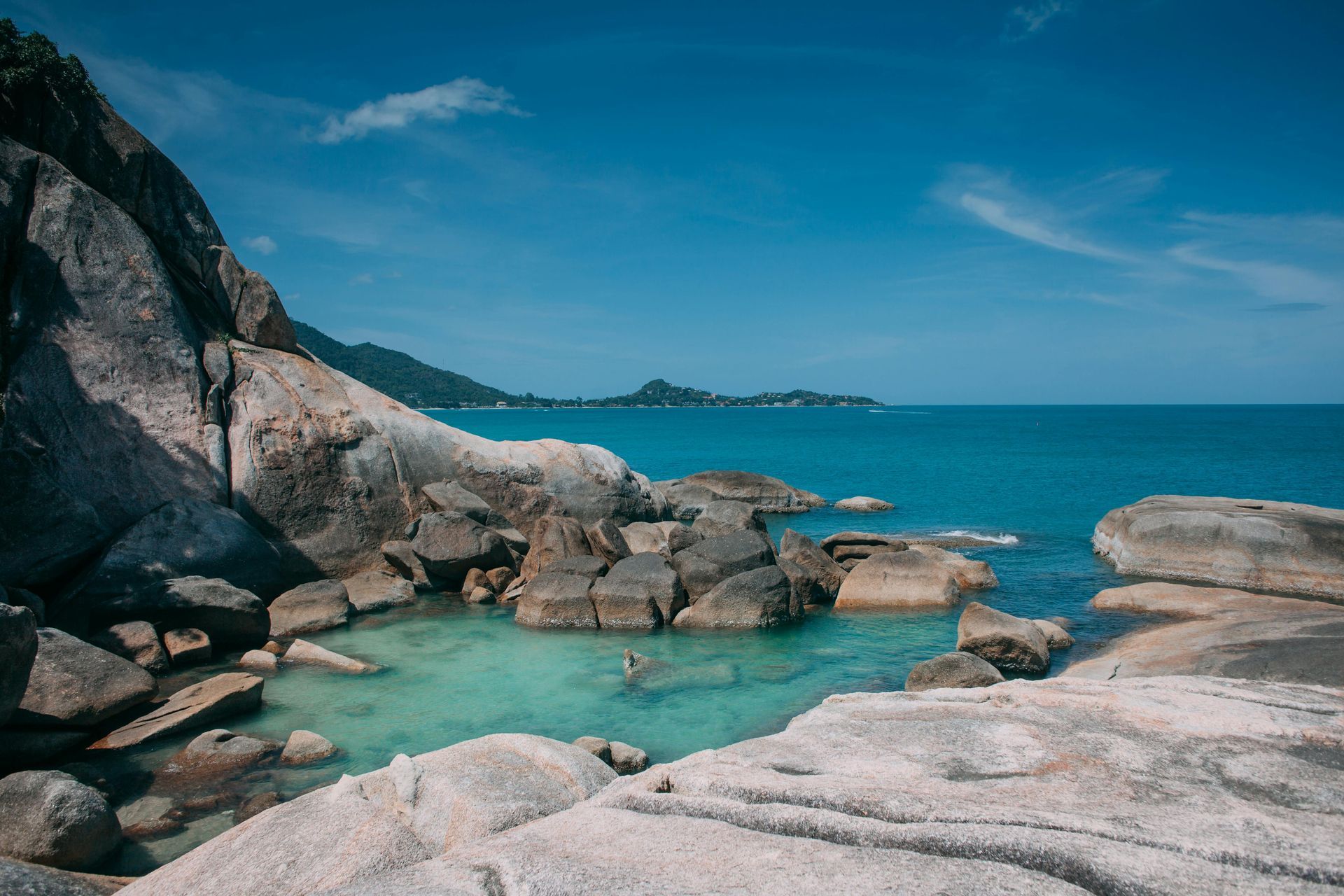 Rocky coastline with clear turquoise water and blue sky.