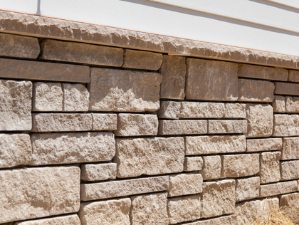 Stone brick wall beneath a white building, with a textured top border.