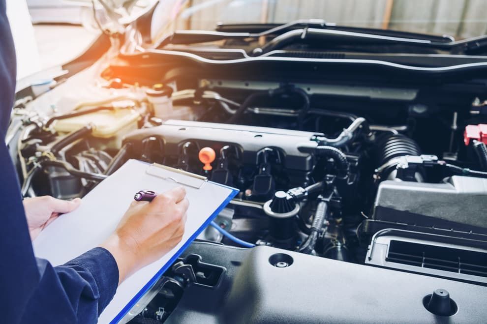 Mechanic Writing On A Clipboard While Examining The Engine Of A Car — Passfield Automotive and Electrical In Cessnock, NSW