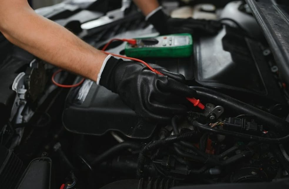 A Man Is Working On A Car Engine With A Multimeter — Passfield Automotive and Electrical In Cessnock, NSW