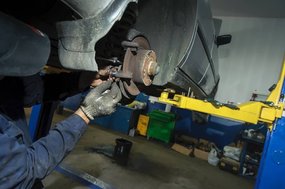 A Man Is Working On A Car On A Lift In A Garage — Passfield Automotive and Electrical In Cessnock, NSW