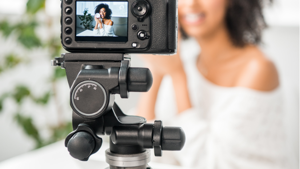 Camera on tripod recording a smiling Black woman indoors.
