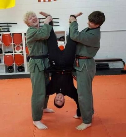 Two men are holding a woman upside down in a gym