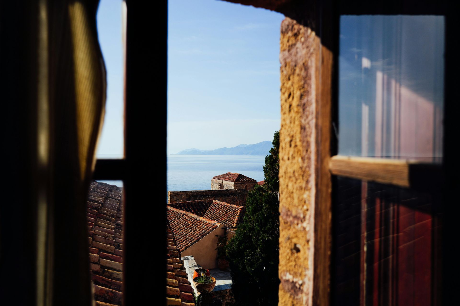 Gentle light through curtain fabric and window with ocean view as a symbol of softness and grounding