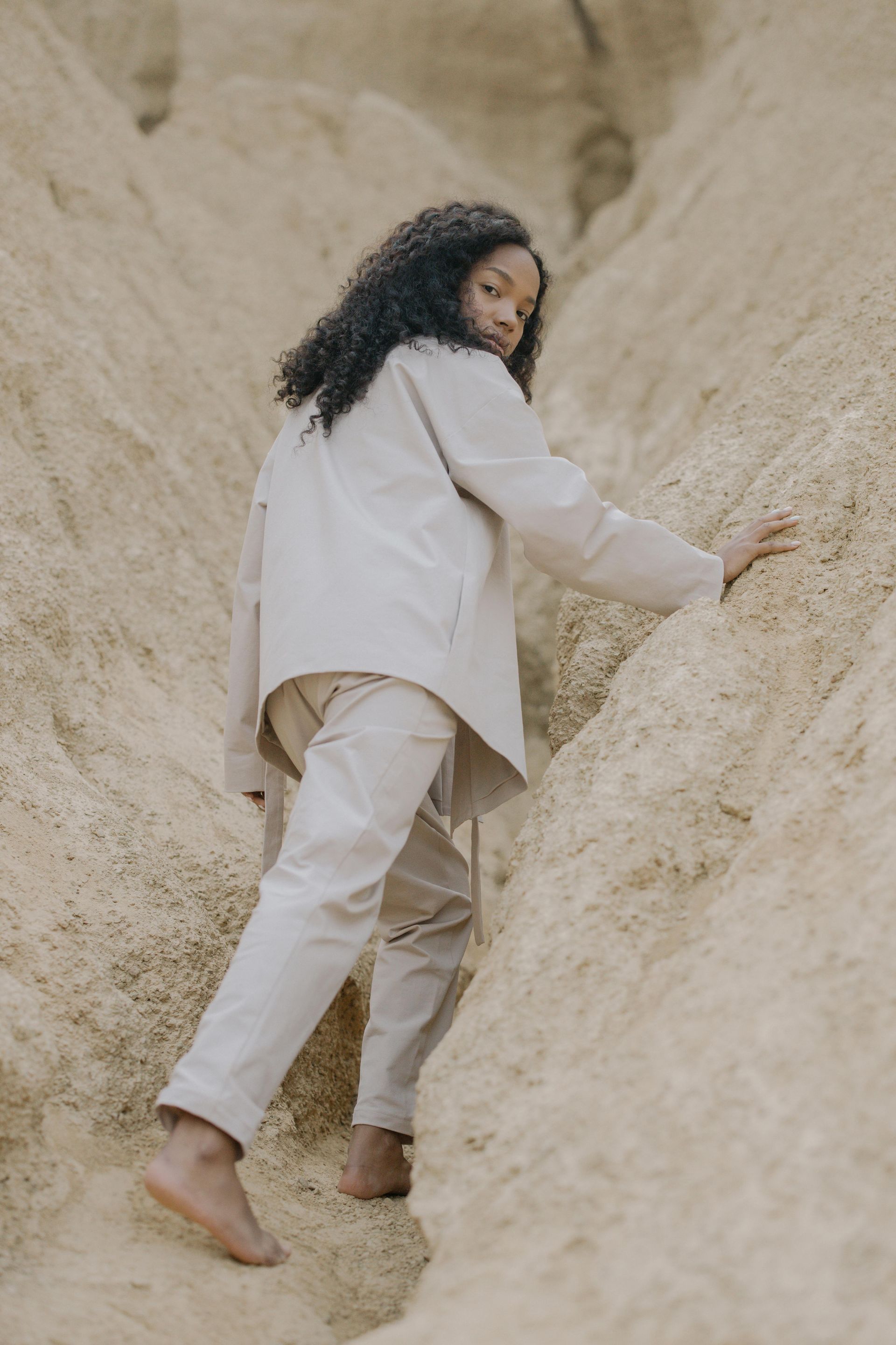 Individual in neutral suit climbing a rock formation symbolizing courage through life’s journey