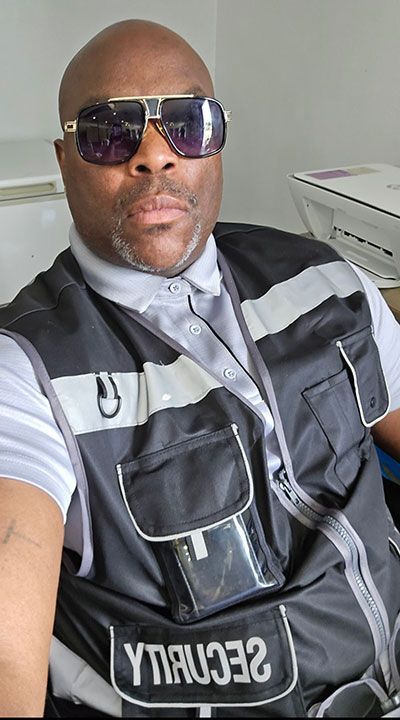 Man in security vest and sunglasses, indoors.