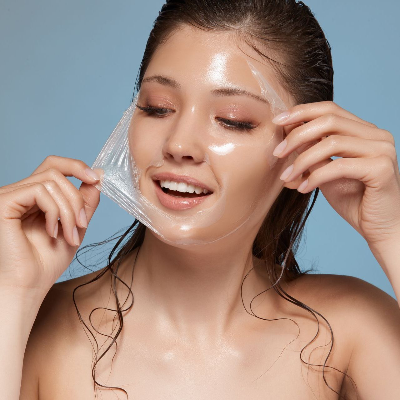 A woman is peeling off a clear Rejuv peel mask from her face.