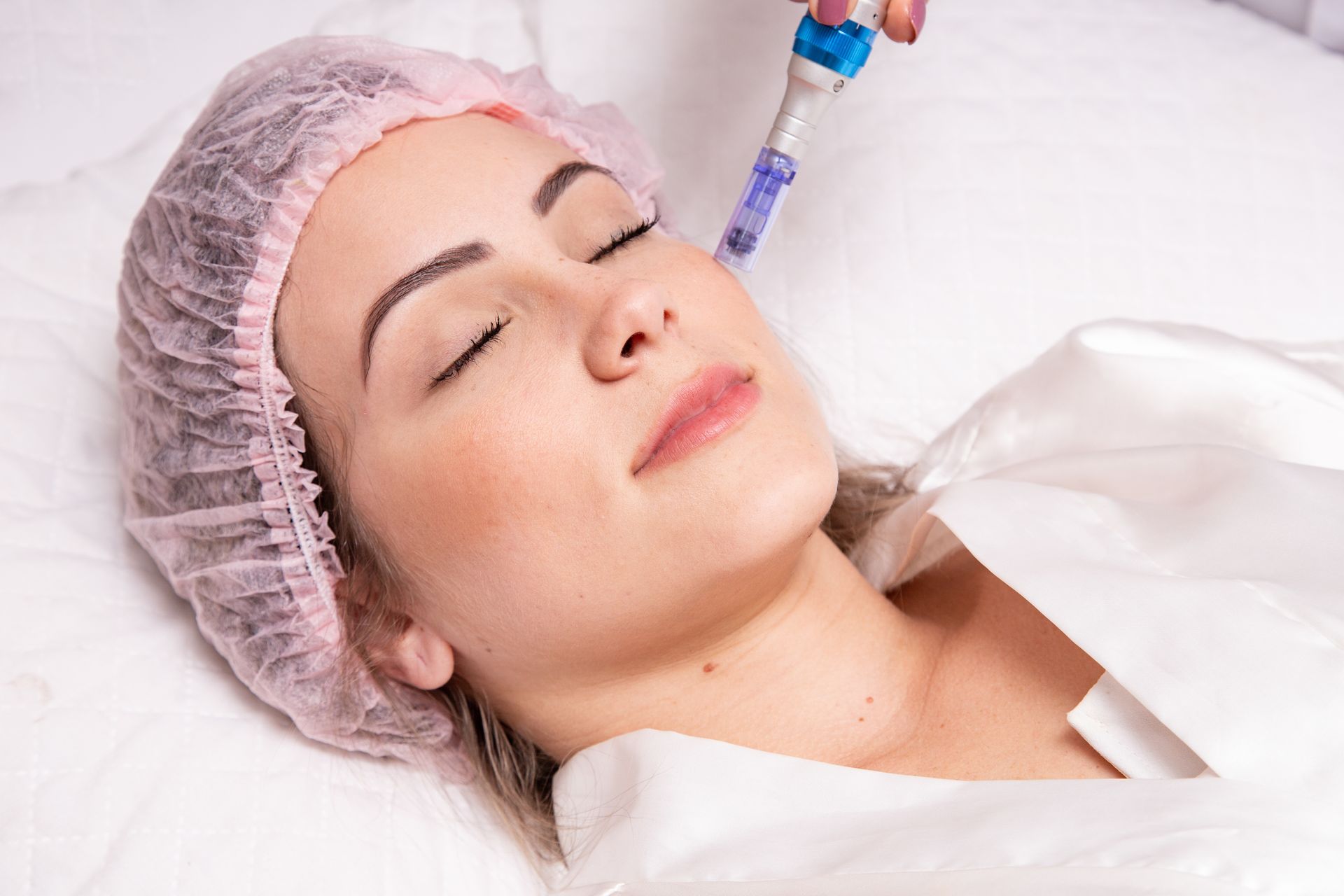 A woman is laying on a bed getting a facial treatment.