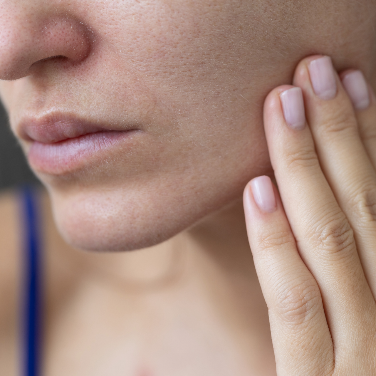 Close-up of woman's face with her hand on it.