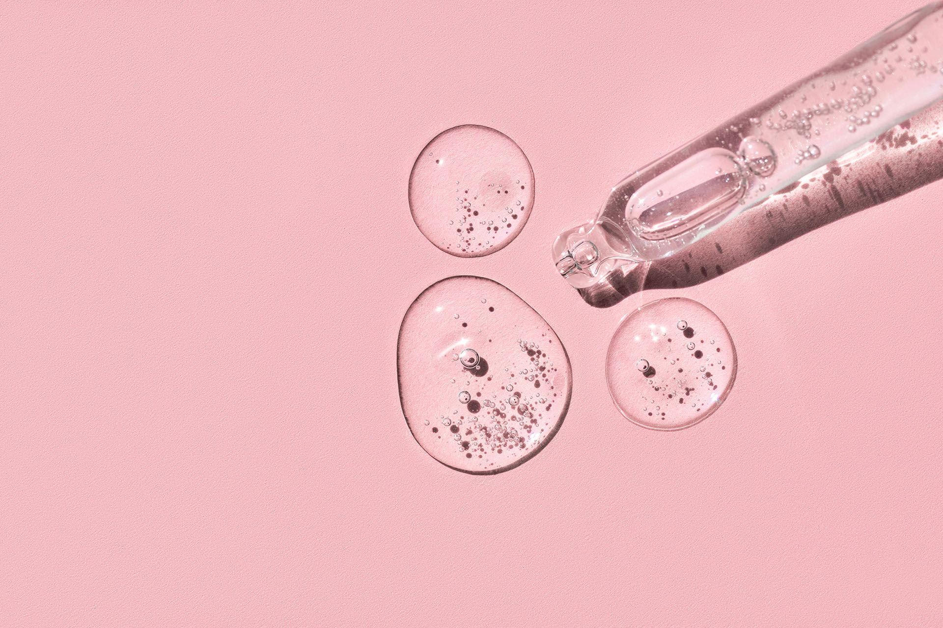 A pipette is being used to apply a liquid to a pink surface.