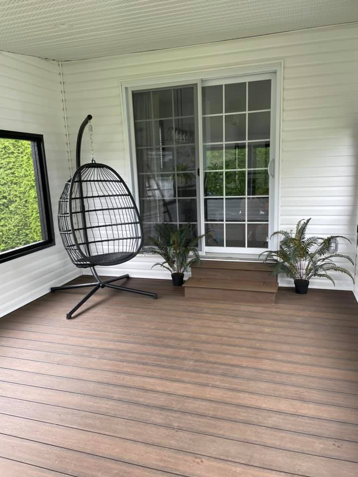 Un porche couvert avec une chaise suspendue en forme d'œuf, une porte coulissante en verre et des plantes en pot.
