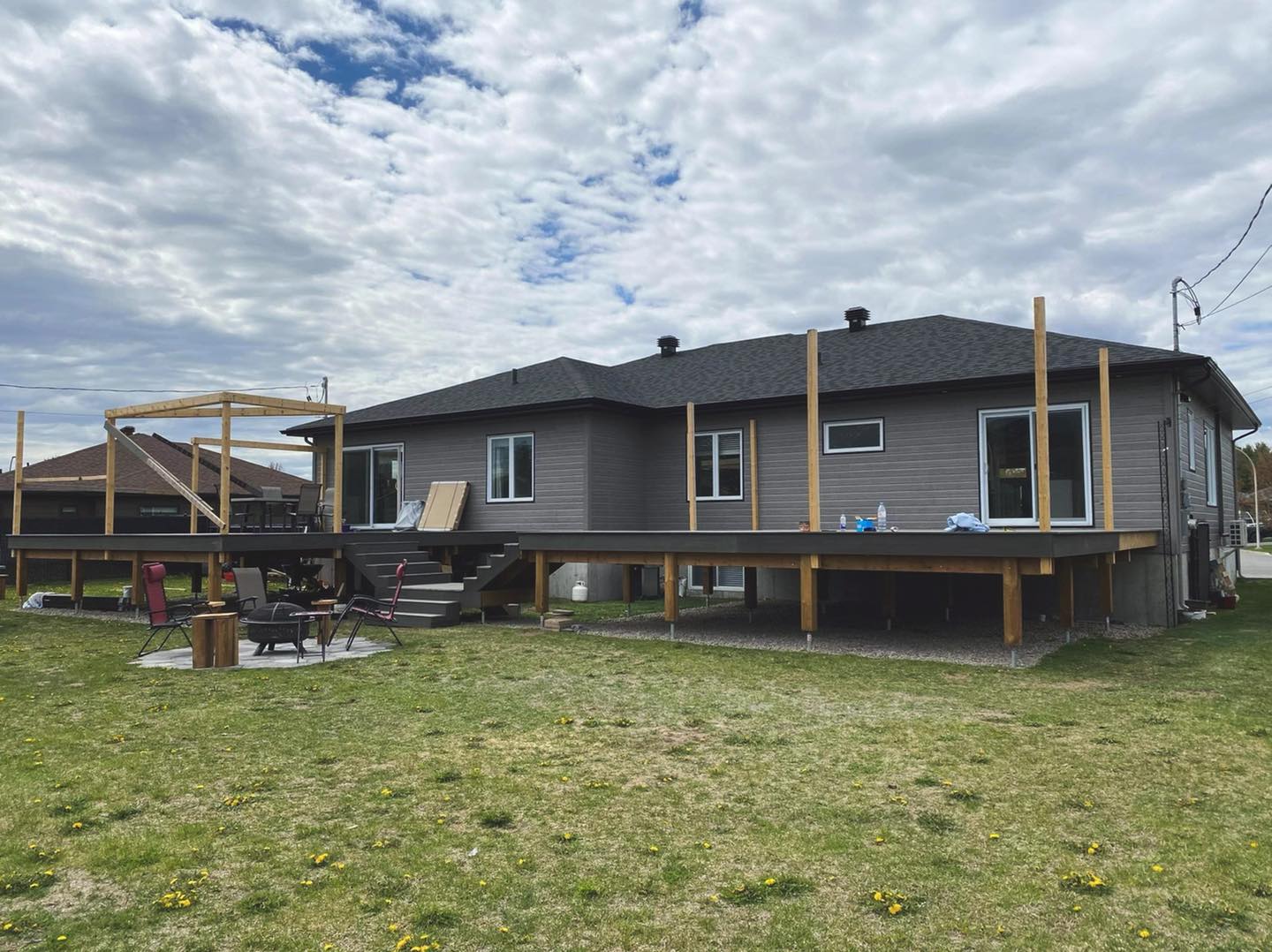 Une maison avec une grande terrasse est située au sommet d'un champ vert luxuriant.