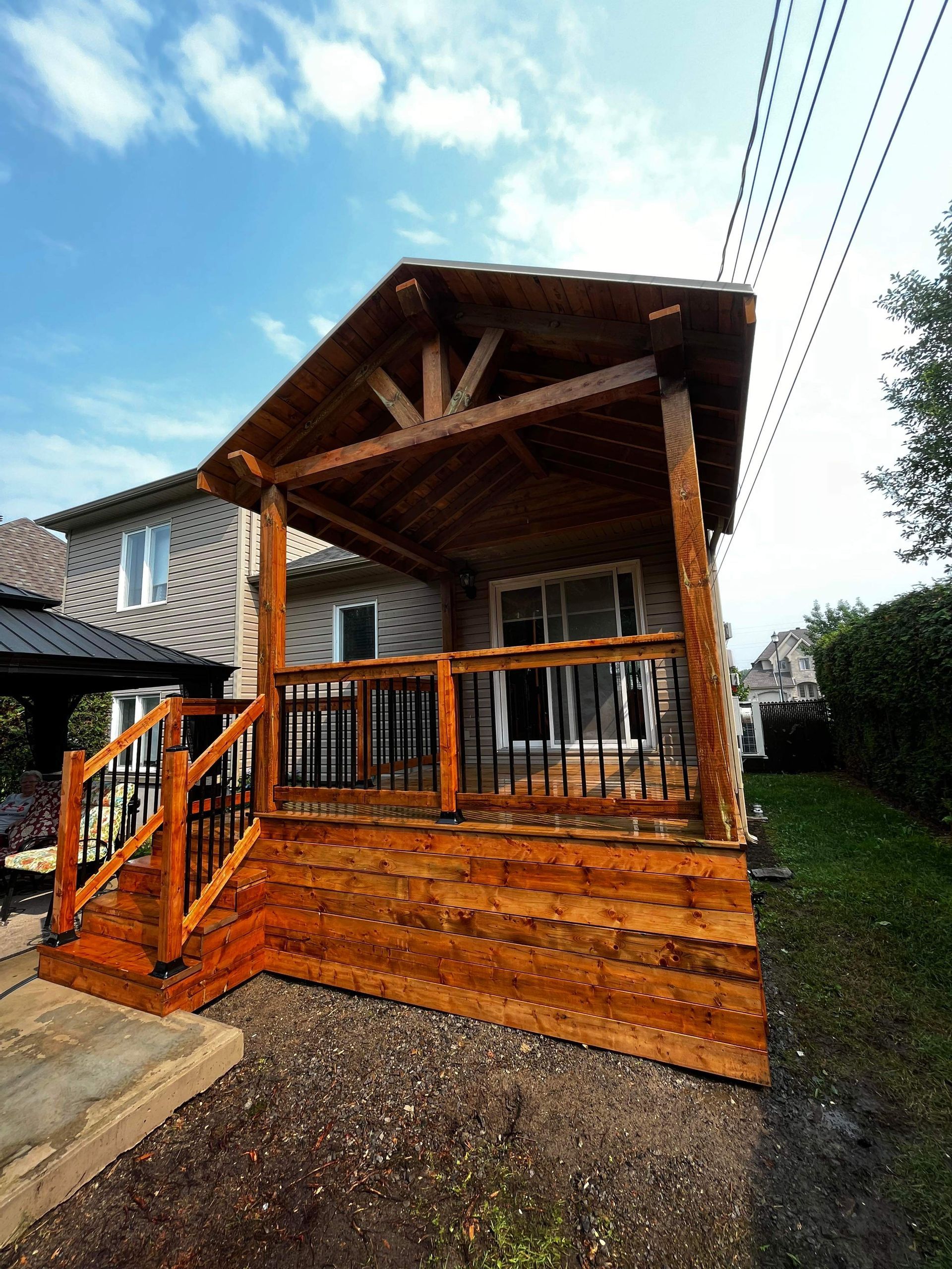 Une terrasse en bois avec des escaliers qui y mènent se trouve devant une maison.