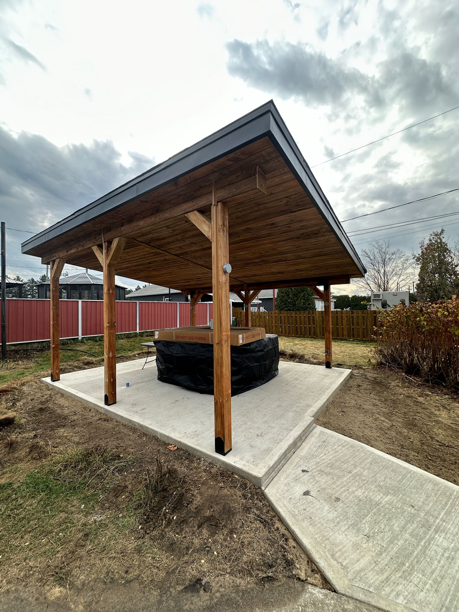 Un belvédère en bois avec un bain à remous en dessous dans une cour arrière.