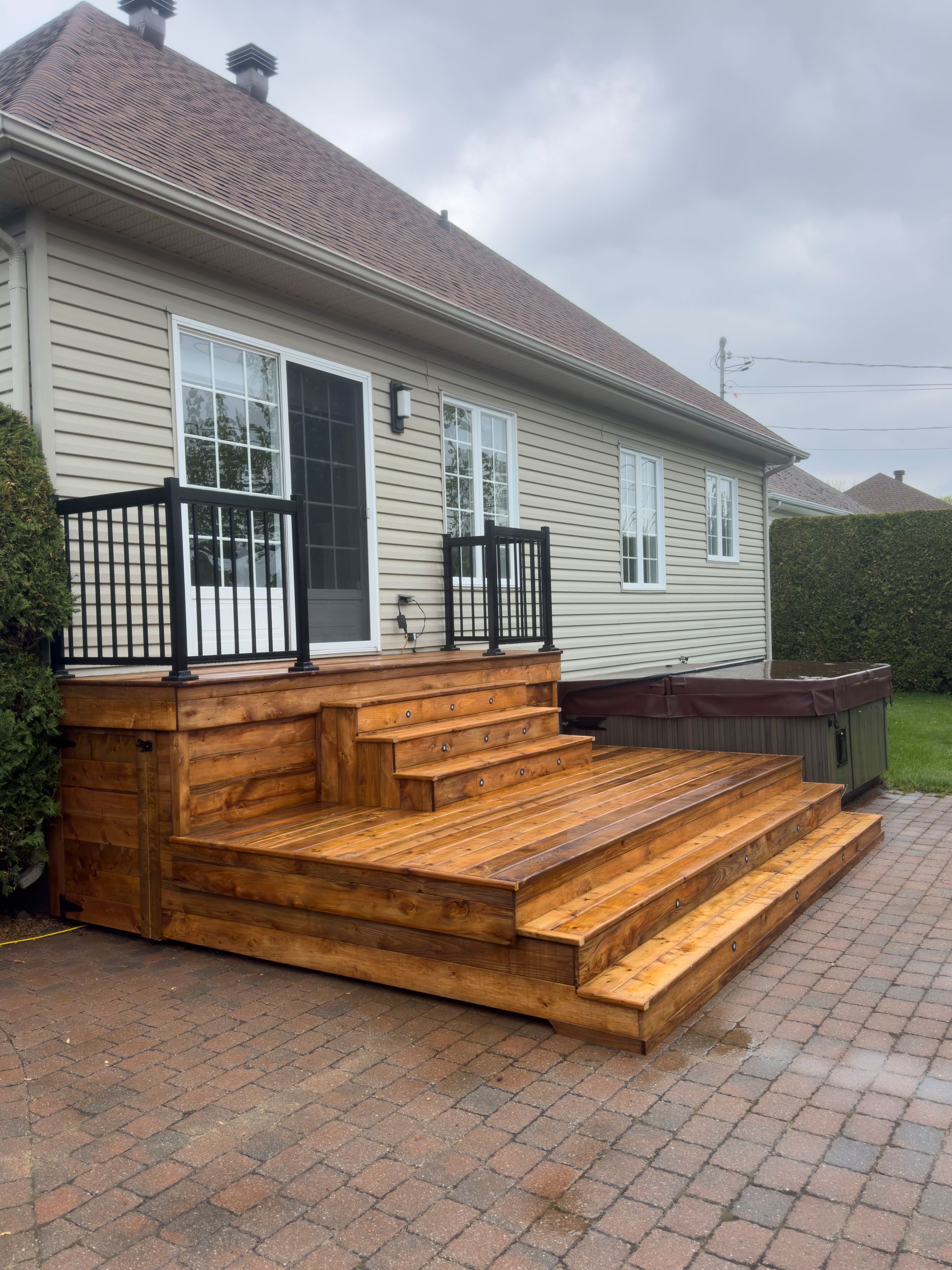 Une terrasse en bois avec des escaliers se trouve devant une maison.