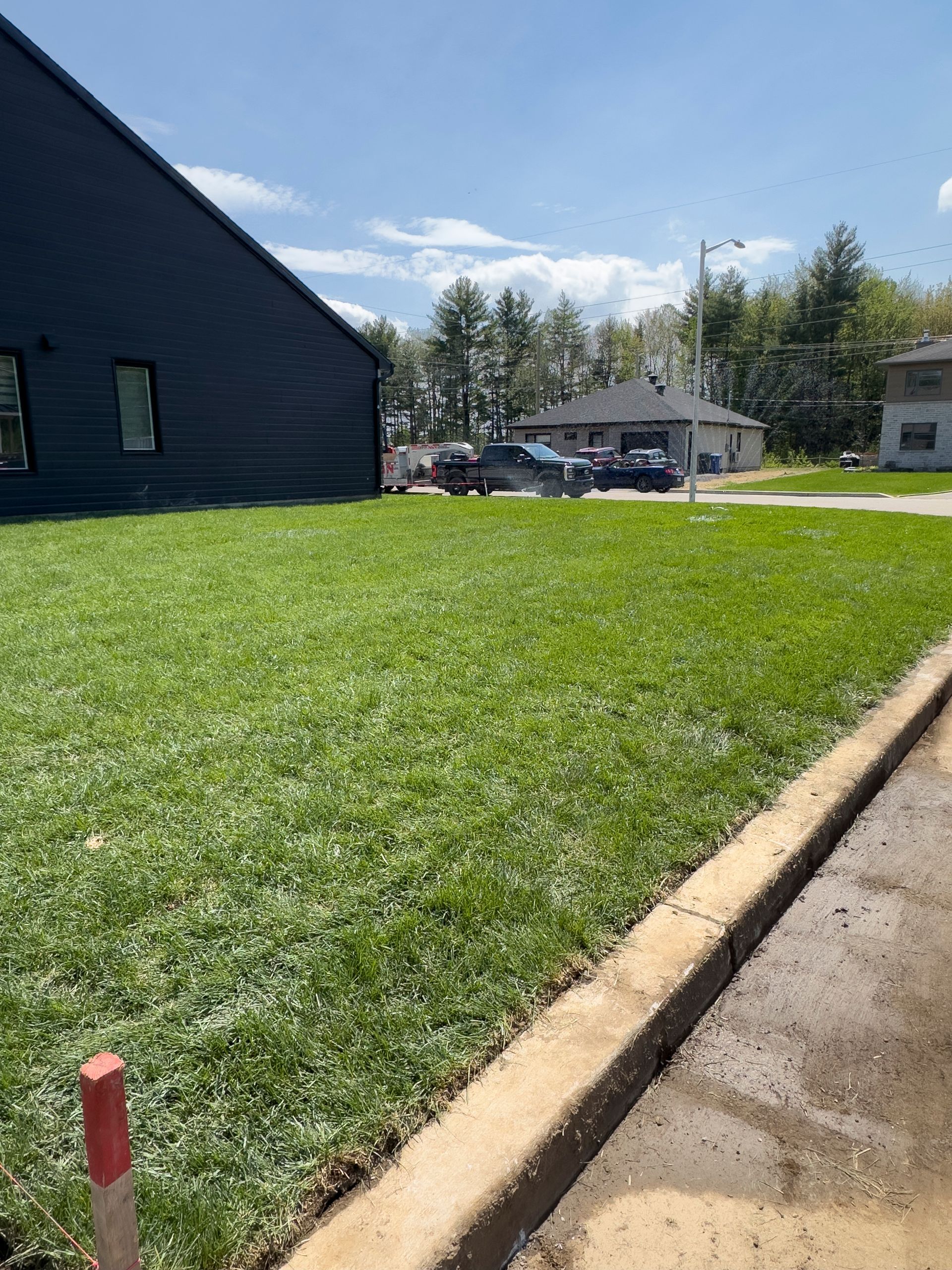 Une pelouse verte luxuriante avec une maison en arrière-plan et un poteau rouge au premier plan.