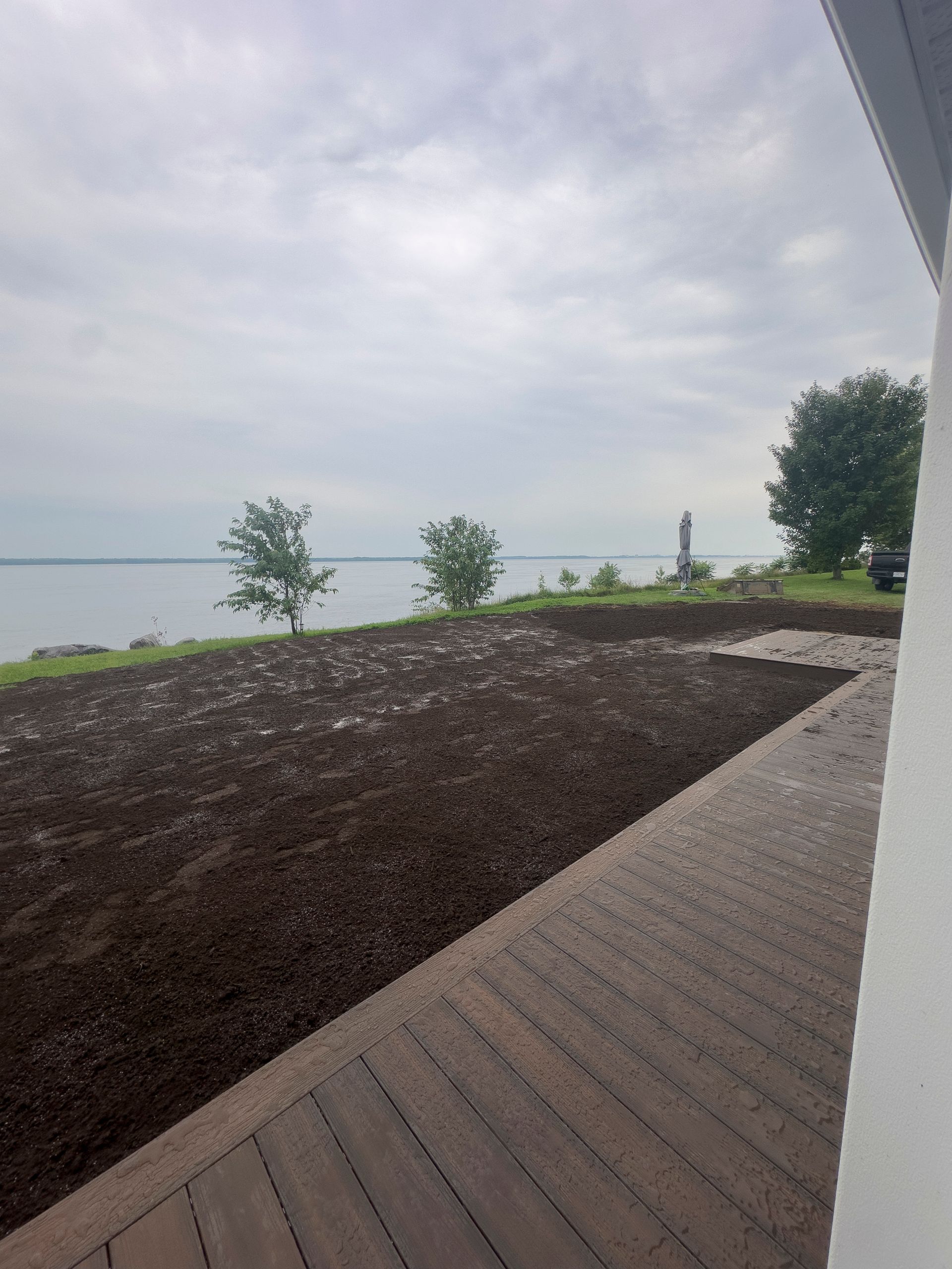 Un patio avec vue sur un plan d'eau et des arbres.