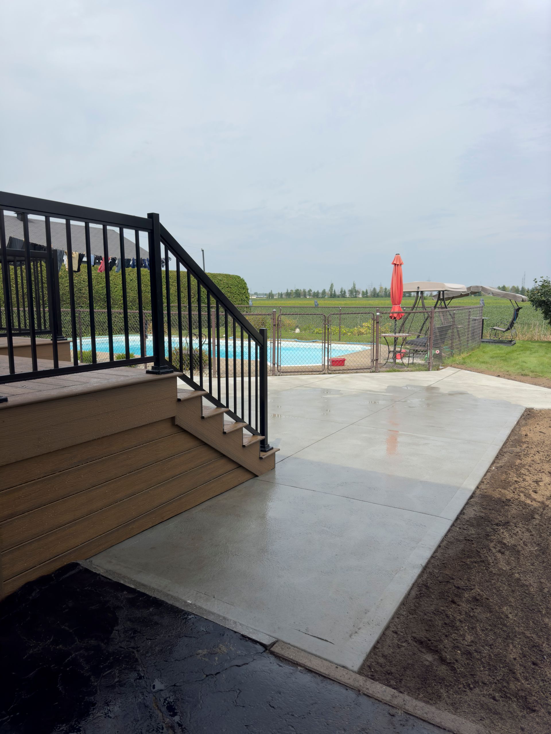 Un patio en béton avec des escaliers menant à une piscine.