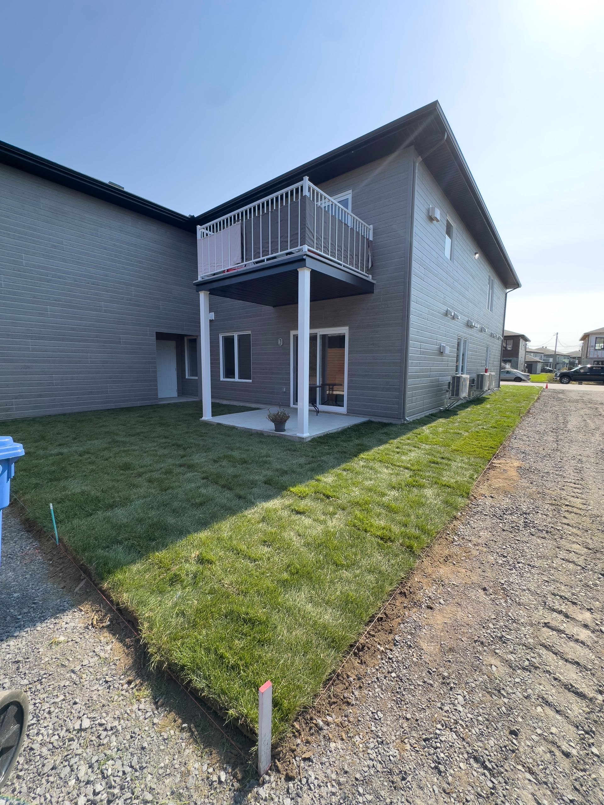 Une maison avec un balcon et beaucoup d'herbe devant.